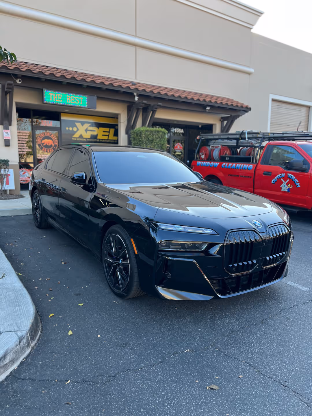 Black BMW 7 Series sedan with ceramic window tint outside Tint Masters