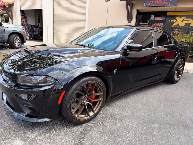 Black Dodge Charger Hellcat with dark tinted windows parked outside Tint Masters