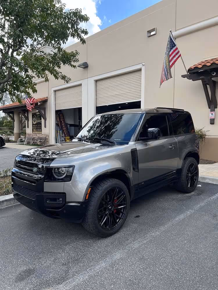 Silver Land Rover Defender with dark window tint parked outside Tint Masters