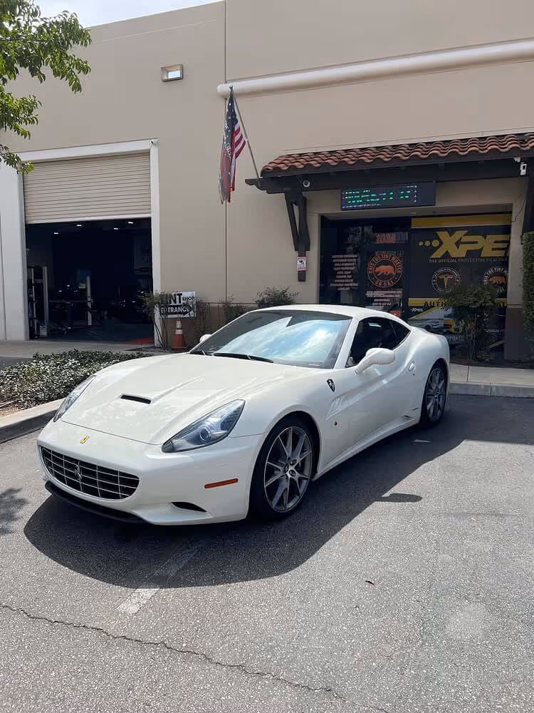 White Ferrari California with dark window tint parked outside Tint Masters