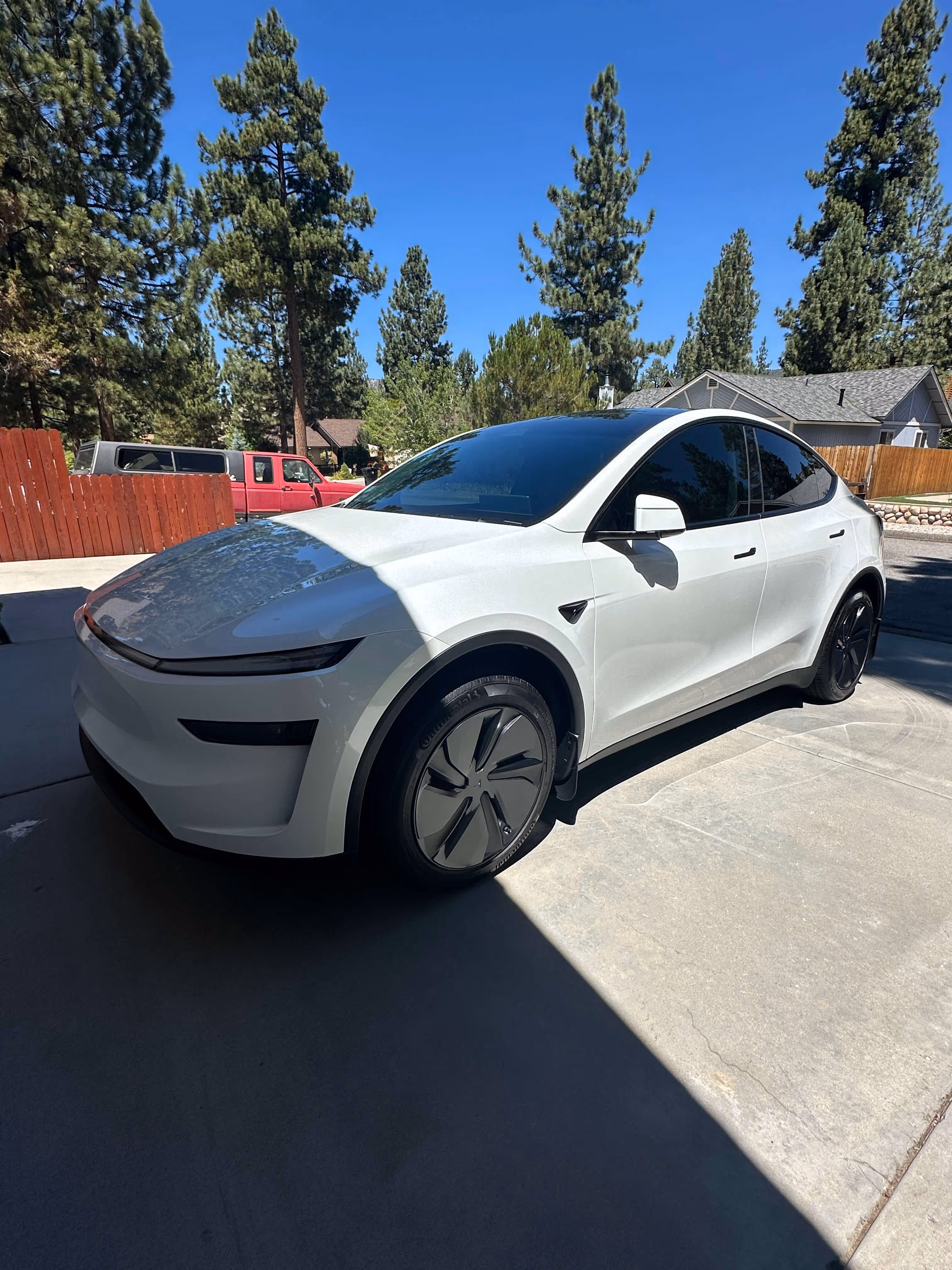 White Tesla Model Y with dark ceramic window tint parked in residential driveway